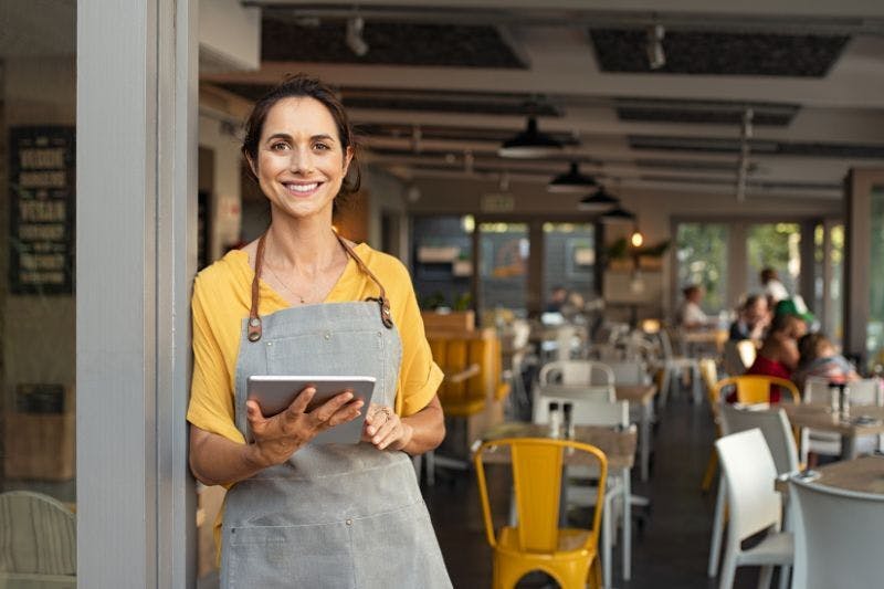 Busy owner holding a tablet, considering outsourcing bookkeeping tasks