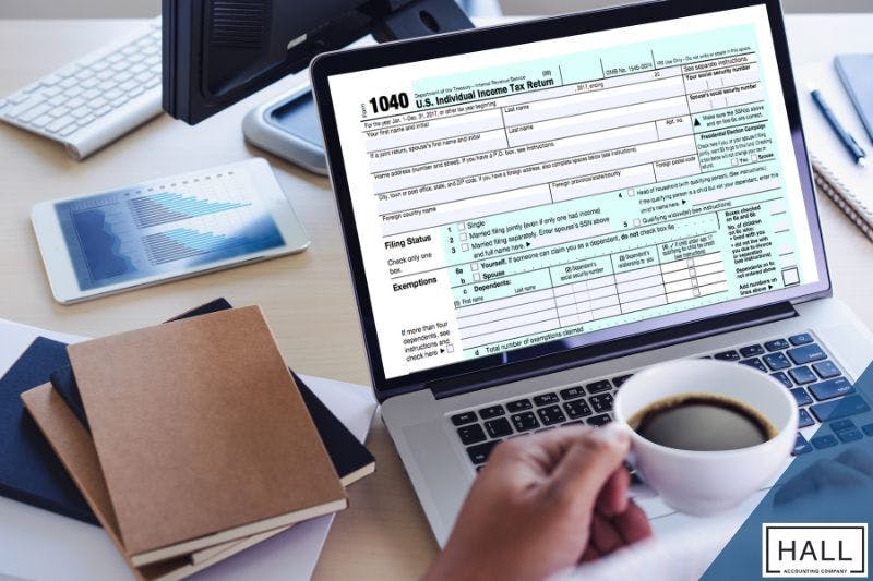 Person holding a coffee cup while reviewing a 1040 tax form on a laptop, emphasizing the importance of proactive tax planning strategies.