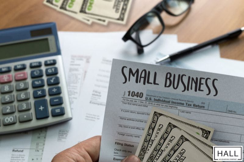 Accounting costs for small business shown with tax forms, cash, calculator, and financial paperwork