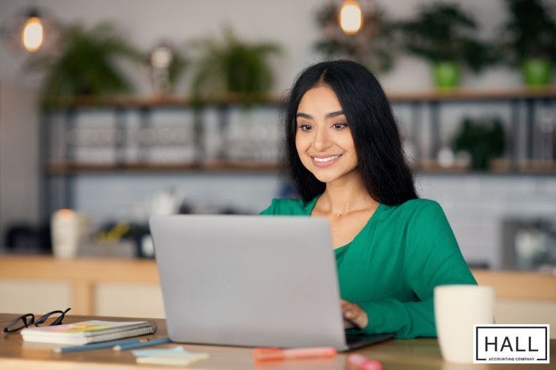 A woman sits at a desk in a café working remotely or part-time, a common scenario for those seeking clarity on how the IRS defines and taxes part-time employment.