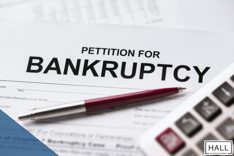 bankruptcy petition form, pen, and calculator, symbolizing financial struggles and debt relief options