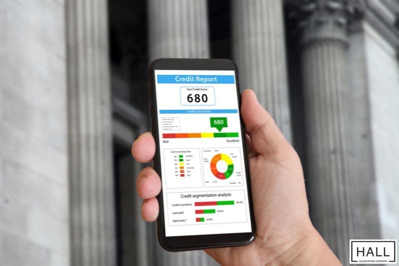 A hand holding a smartphone displaying a credit report.