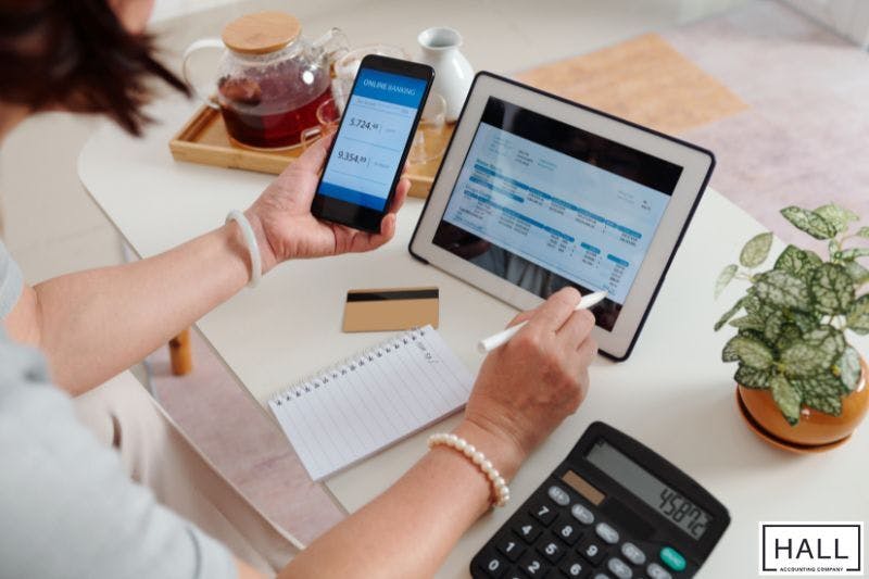 Person using tablet and phone for finances, illustrating how much does bookkeeping cost a business.