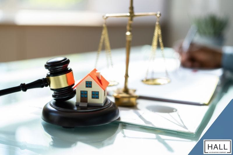 A judge's gavel resting on a small model house, with a scale of justice and legal documents that symbolizes the legal process involved in purchasing tax lien properties in Texas