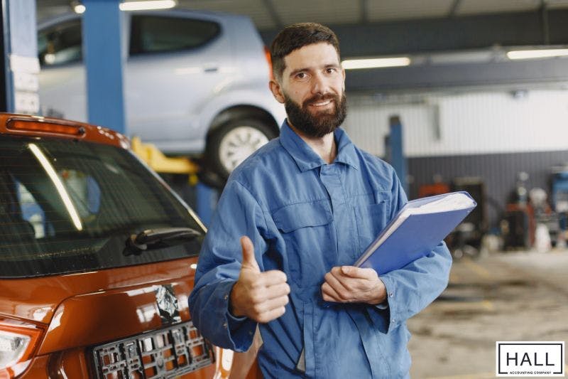 Mechanic giving thumbs up in garage, symbolising confidence in buying a new car tax deductible in Texas.