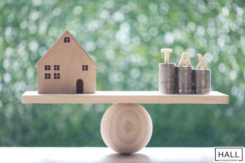 House figure and tax coins balanced, symbolizing property tax rate in San Antonio TX.