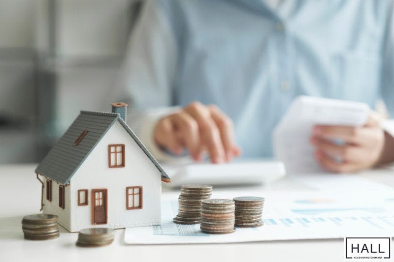 Miniature house and stacked coins representing property tax rate in San Antonio TX.