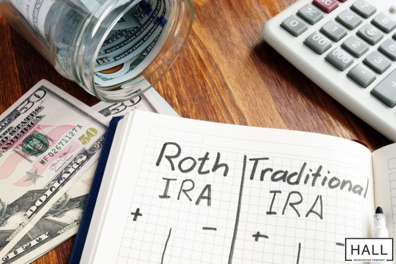 A notebook page with "Roth IRA" and "Traditional IRA" written on it, separated by a plus and minus sign.