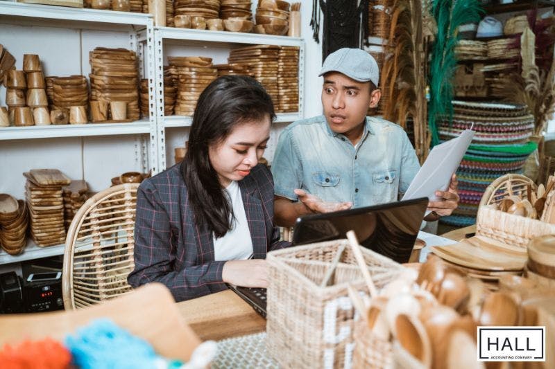 Two business owners, one looking disturbed, reviewing sales documents, highlighting potential sales tax errors.