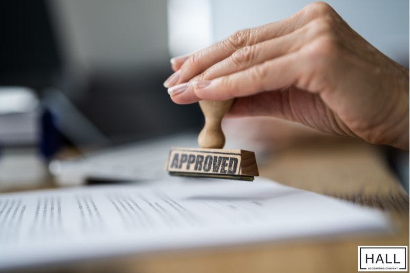 Hand stamping approval on documents, representing verified sales tax in San Antonio, Texas paperwork.