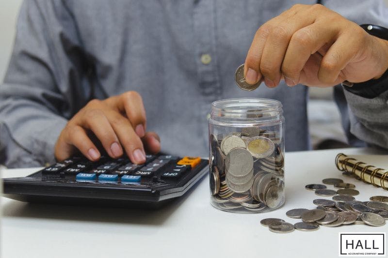 Person calculating coins and savings, illustrating impact of sales tax in San Antonio, Texas.
