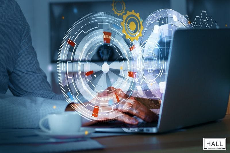 A person uses a laptop with futuristic data overlays, symbolising technology’s role in efficiently managing small business taxes.