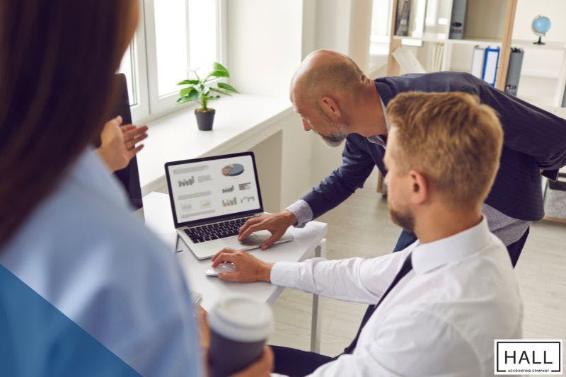 Team discussing tax planning strategies for individuals in 2025, analyzing charts and data on a laptop in a modern office.