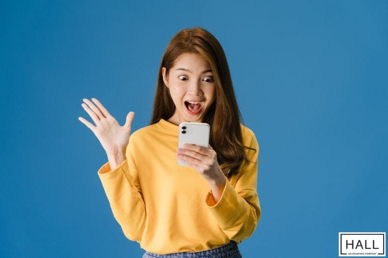 A surprised woman checking her phone, representing tax refunds or deductions