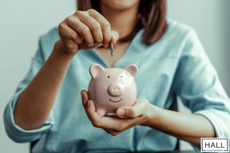 Woman placing coin in piggy bank—why is receiving a large tax refund a bad thing?