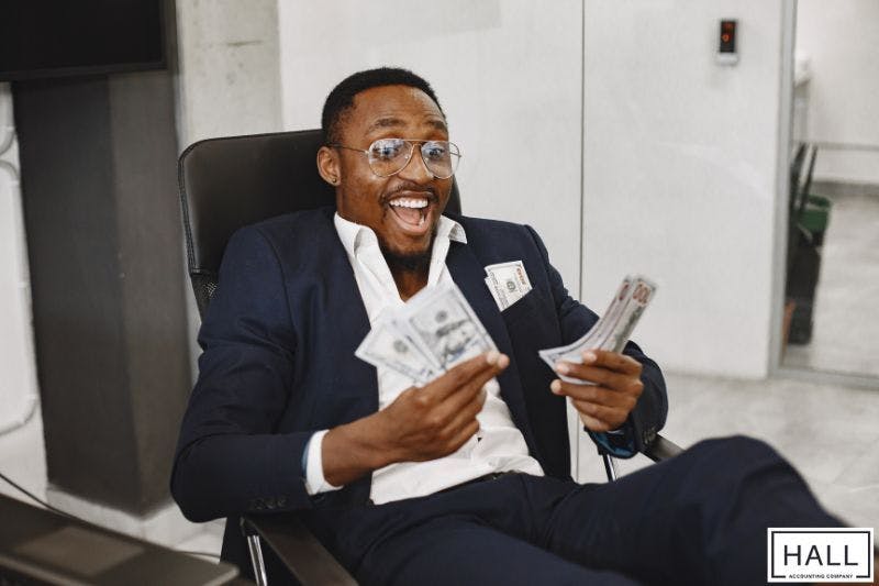 Man excitedly holding cash—why is receiving a large tax refund a bad thing?