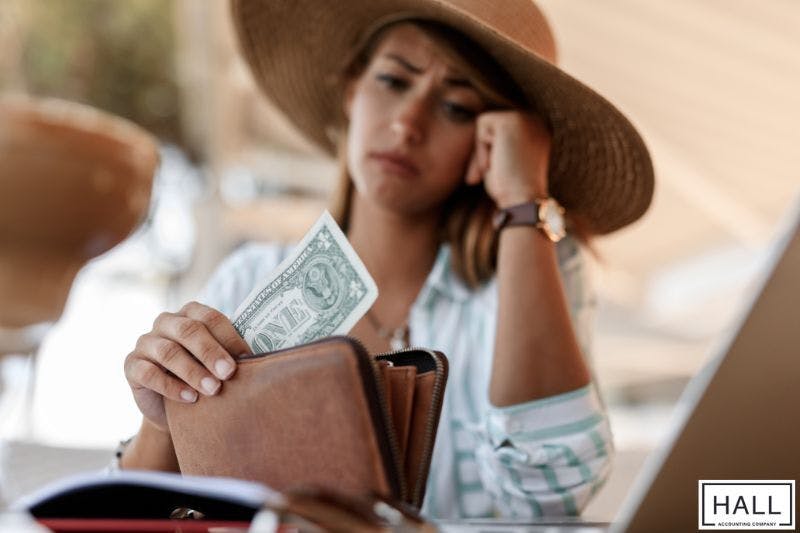 Worried woman holding a dollar—why is receiving a large tax refund a bad thing?