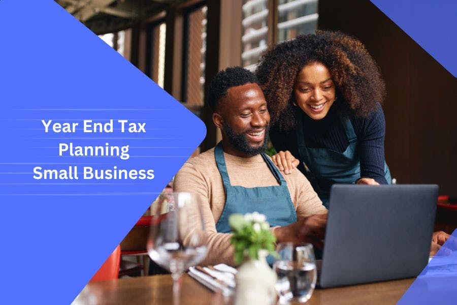 Two small business owners happily reviewing financial documents on a laptop in a restaurant, symbolising effective year-end tax planning strategies.