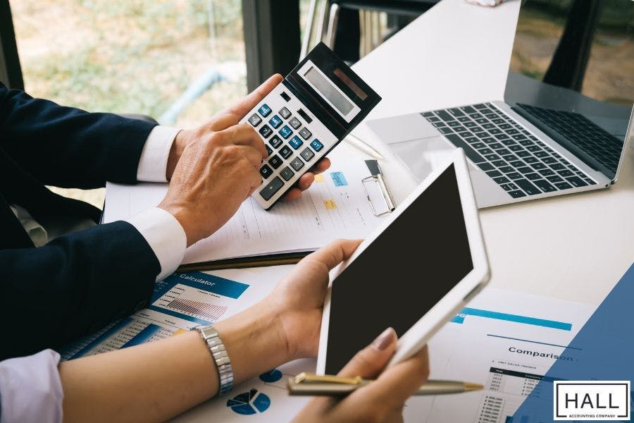 Business professionals using a calculator, tablet, and laptop to review financial documents, highlighting strategic year-end tax planning for small business owners.